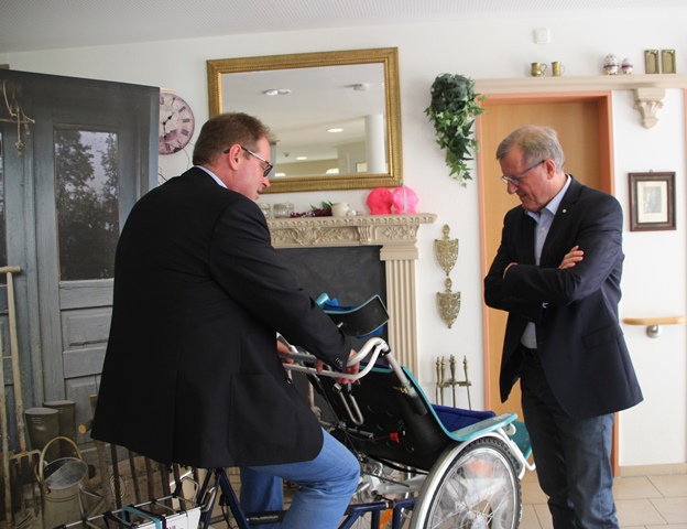 Jürgen Coße testet das Rollstuhlrad im Foyer des Seniorenzentrums; Wilhelm Schmidt sieht ihm dabei zu.